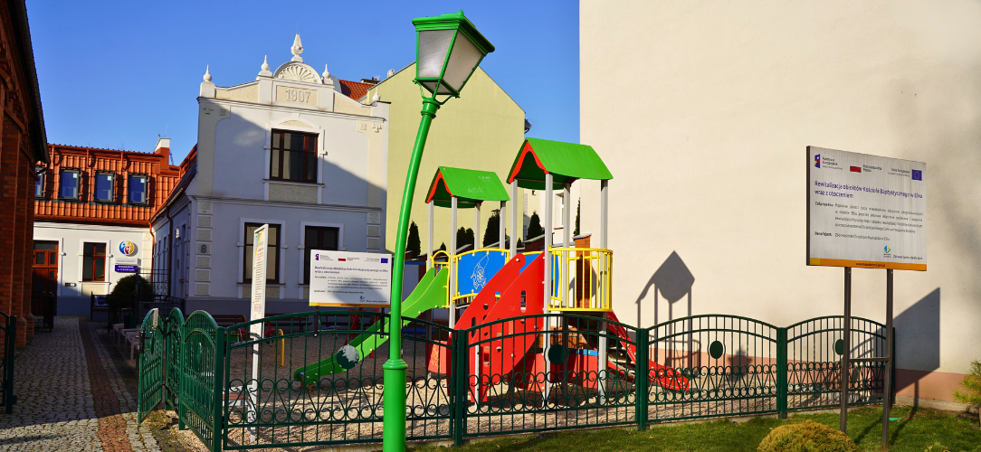 Zdjęcie przedstawia budynek Przedszkola w Centrum z placem zabaw.